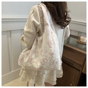 Detailed close-up of white lace tote bag with pink butterfly embroidery and raw edges