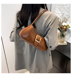 Brown semi-circle shoulder bag with large gold buckle worn by model from behind