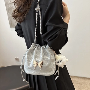 Silver metallic pleated bucket bag with butterfly decor and plush charm on chain strap