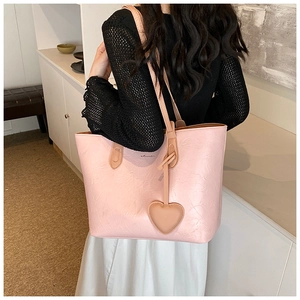 Detailed texture of pink embossed leather tote bag with a matching heart charm accessory