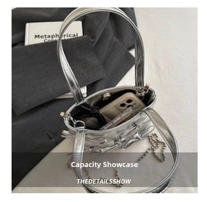 Silver metallic mirror handbag with bow details showing internal capacity and chain strap