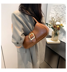 Detail of brown glossy underarm bag with gold metal buckle on a grey suit jacket