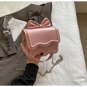 Detailed view of pink crossbody bag with bow decoration and silver chain strap