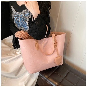 Close-up of pink tote bag with wrinkle texture and heart charm in a lifestyle setting