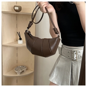 Gros plan du sac croissant marron foncé montrant la texture plissée et le détail du nœud