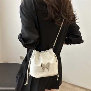 Minimalist white bucket bag with silver butterfly accent and metal chain shoulder strap