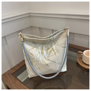 Detailaufnahme der goldenen Bambusstickerei und Metallbeschläge an der Seidenschultertasche