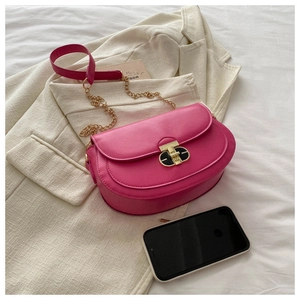 Detail of fuchsia crescent crossbody bag with golden chain strap and oval metal buckle