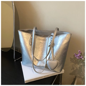 Detail of silver tote bag with crinkled metallic texture and heart charm decoration