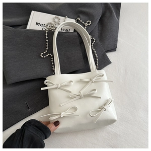 Detail of white PU leather bag featuring ribbon bows and silver bead chain strap