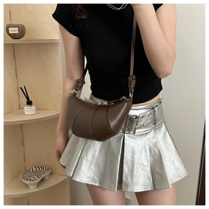 Détail du sac croissant en cuir marron foncé avec design plissé et bandoulière à nœud