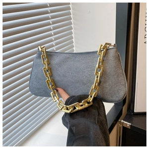 Detail of grey suede shoulder bag featuring a chunky gold rectangular metal chain