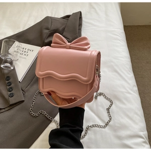 Pink crossbody bag detail showing bow decoration and elegant wavy flap edge
