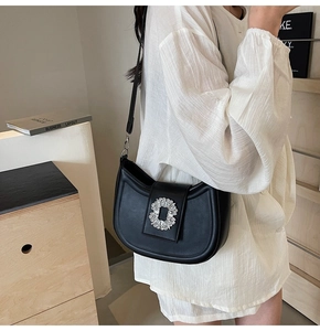 Detail of black matte leather saddle bag featuring a sparkling crystal ring buckle