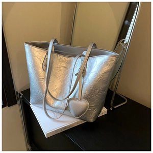 Close-up of silver tote bag with metallic crinkled texture and heart-shaped charm accessory
