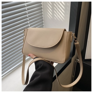 Detail view of the sleek beige shoulder bag flap and smooth PU leather texture