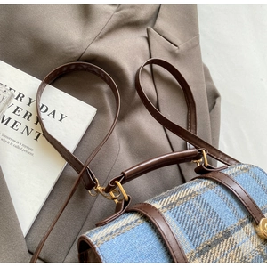 Detailed close-up of British style tweed backpack with brown leather straps and gold metal rings