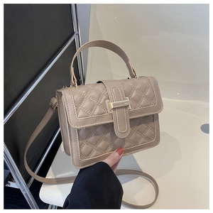 Detail of beige quilted handbag with golden metal clasp and fine synthetic leather texture