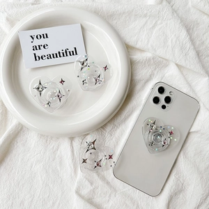 Sparkly heart phone grip with rhinestones and star sequins on a white smartphone