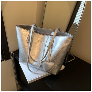 Close-up of metallic silver tote bag with crinkled texture and heart-shaped charm accessory