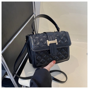 Detail shot of black quilted leather bag featuring a gold rectangular metal clasp
