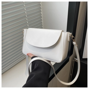 Close-up of white minimalist crossbody bag in smooth matte leather with golden hardware