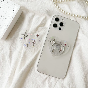 Sparkly heart phone grip with glitter stars and rhinestones on a white smartphone