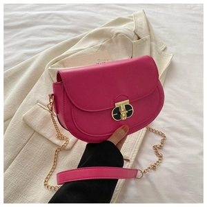 Detail of rose pink saddle bag with gold chain strap and modern metal buckle closure