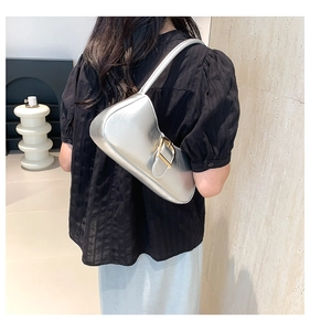 Silver metallic hobo bag with gold adjustable buckle worn over shoulder on model