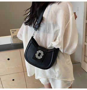 Detail of a black hobo bag featuring a sparkling rhinestone buckle and sleek leather strap