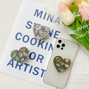 Sparkling heart-shaped phone grip with colorful rhinestones on a white smartphone
