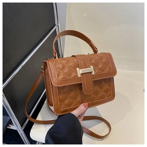 Detail of a brown quilted crossbody bag with golden clasp and adjustable shoulder strap
