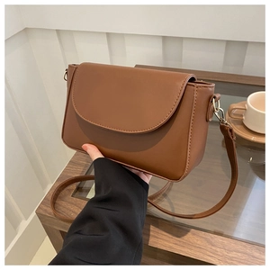 Detailed view of the brown leather crossbody bag with stitching and gold hardware details