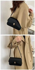 Detail of minimalist black leather underarm bag with elegant gold square buckle clasp