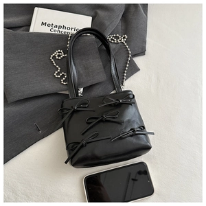 Close-up of black mini tote bag with decorative bows and silver beaded chain detail