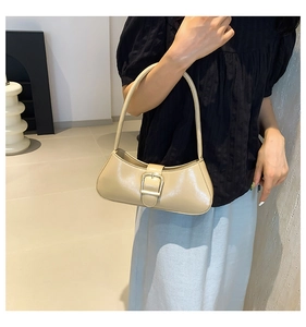 Close-up of beige glossy underarm bag featuring a metallic square buckle detail