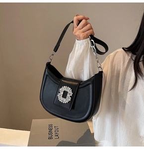 Close-up of black hobo bag featuring a luxury crystal flower buckle and leather strap