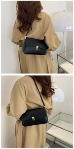 Detail of elegant black leather handbag featuring a square gold metal buckle and slim strap