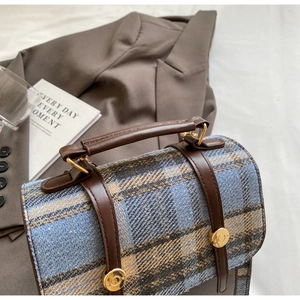Detail of British style tweed backpack with brown leather straps and gold metal buckles