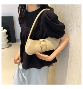 Detail showing high-gloss beige leather armpit bag with large gold buckle and shoulder strap