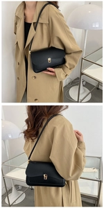 Detailed close-up of a black leather underarm bag with an elegant gold square lock buckle