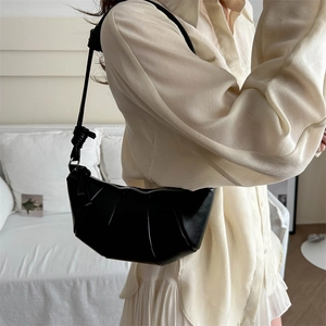 Sac croissant noir plissé avec détail de nœud porté par un mannequin élégant