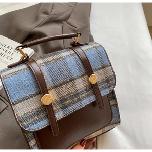 Close-up of British style checkered fabric and brown leather patchwork on handbag