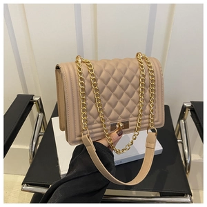 Detailed view of quilted beige shoulder bag featuring a gold chain and metallic lock closure