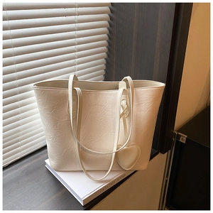 Detailed shot of cream tote bag with ruched texture and heart charm on a wooden window sill