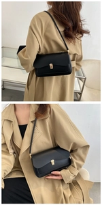 Detail of minimalist black leather shoulder bag featuring a sleek gold rectangular clasp