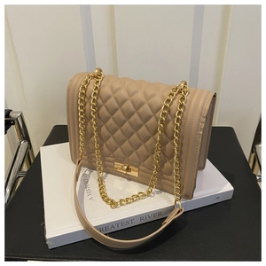 Detail of beige quilted shoulder bag with gold chain strap and textured diamond pattern