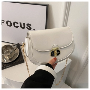 Close-up of white saddle bag with distinctive gold T-lock and fine chain strap detail
