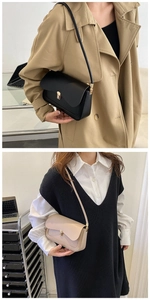 Detail view of the sleek metal square buckle and leather texture on a chic shoulder bag