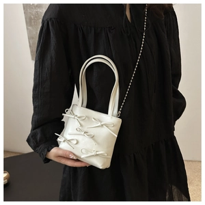 White minimalist crossbody bag with bows paired with a black dress for high contrast